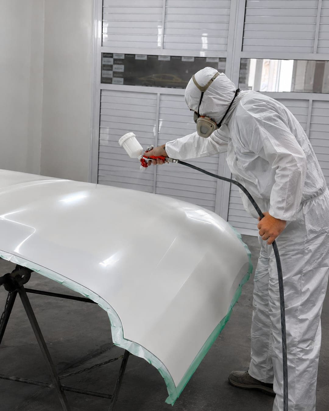 Peça automotiva em cabine de pintura recebendo aplicação de tinta na Exclusive Auto Reparos